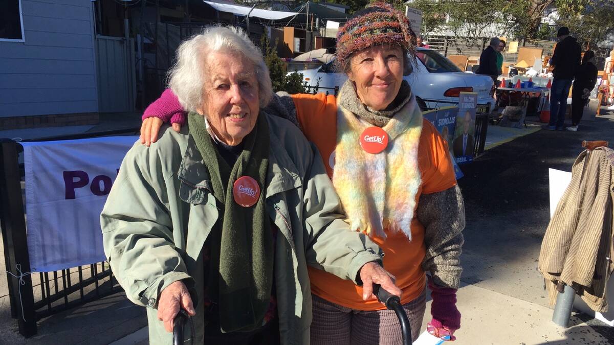 Jean Reid, 100 years, handing out how-to-vote cards for Get Up with daughter Joani at Tomakin on Saturday.