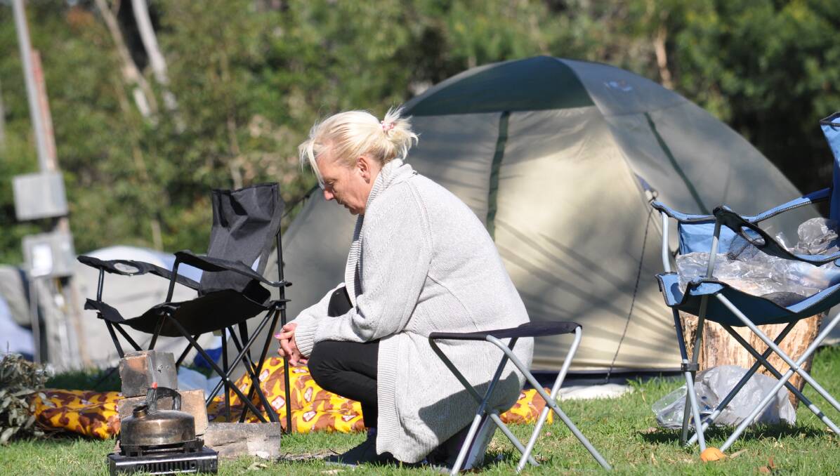 OUT IN THE COLD: Julie, one of a growing band of homeless people camped at Nowra Showground, warms up by a camp stove.  Photo: Adam Wright