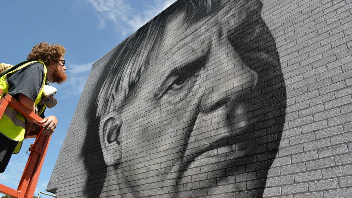 Timeless: New Zealand artist, Owen Dippie finishes work on a mural of famous local artist Arthur Boyd days after recreating David Bowie on a wall in Wollongong as he appeared on his iconic Aladdin Sane album cover. Photo: Jessica Long