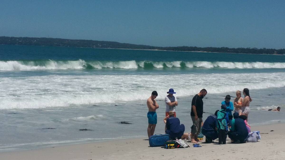 ON DRY LAND: Ambulance paramedics treating a swimmer on Callala Beach today. Picture: Rebecca Potter