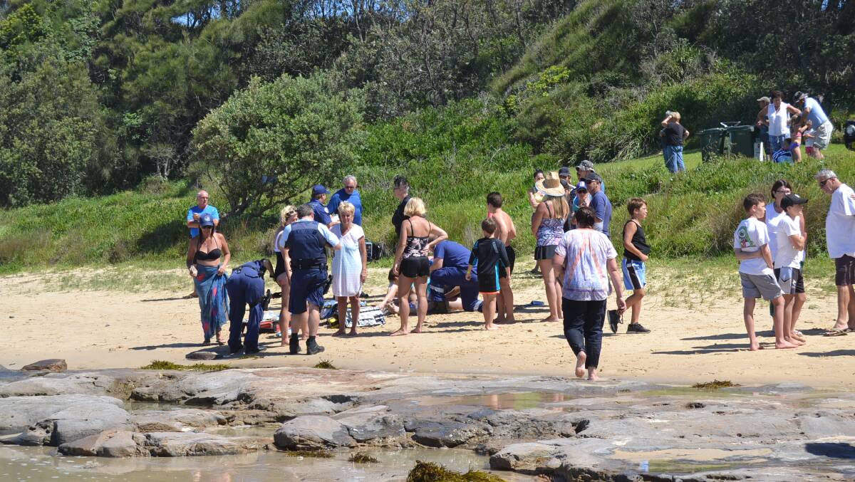 RESCUE: Paramedics treat several people on the shore after seven people and a man who came to their aid were pulled from the water by Dolphin Point resident Damien Martin on Wednesday. Photo: Emily Barton. 