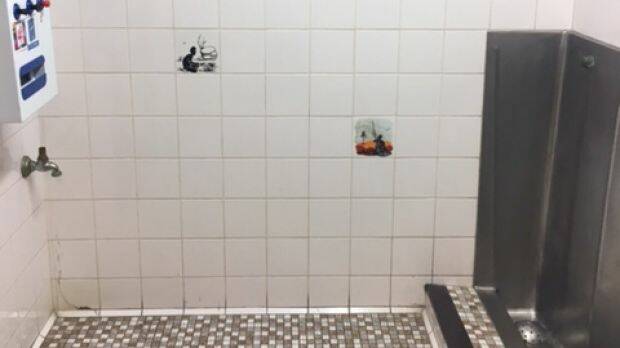 A photograph supplied by ACT Labor politician Bec Cody of the men's urinal at the Sussex Inlet RSL, with tiles depicting Aboriginal men. Photo: Supplied