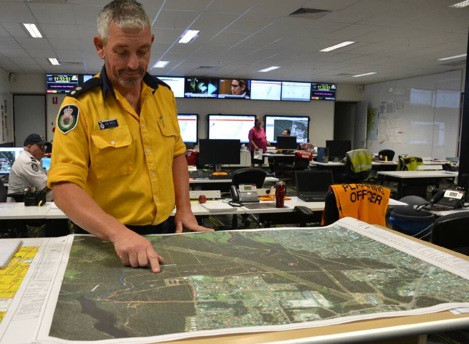 Shoalhaven RFS Superintendent Mark Williams looks over the map of the area burnt out in Monday's fire west of Nowra.
