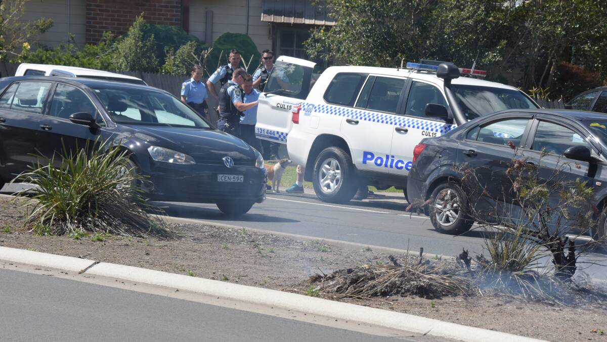 Police arrest a man on the Princes Highway at Bomaderry, the scene of a fire, for a totally unrelated traffic offence.