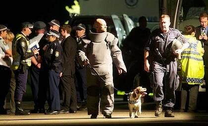 Flash back to 2011 - Senior Sergeant Matthew Warwick (left) emerges from the Pulver home with his then partner, bomb detection dog, Toby the Springer Spaniel. Photo: Brendan Esposito