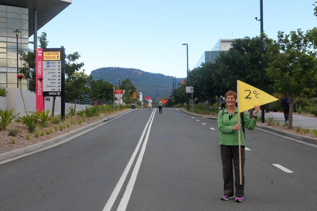 REALITY CHECK: Greens member Anne Marett, and two others, with flags showing where sea levels will rise to at the Innovation Campus if global warming continues. Picture: Adam McLean