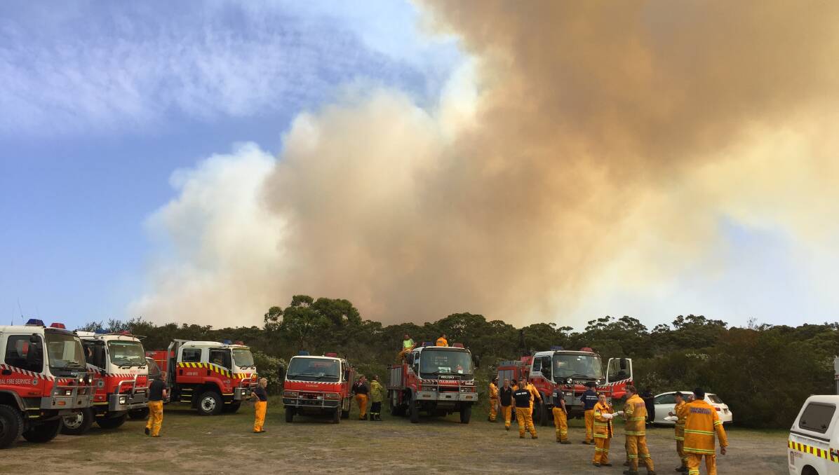 FRIENDLY FIRE: Fire crews watch and wait while a blaze marches through a bombing range toward Currarong.