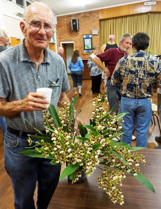 IMPRESSIVE: Don Raffell with his beautiful orchid at the December meeting.