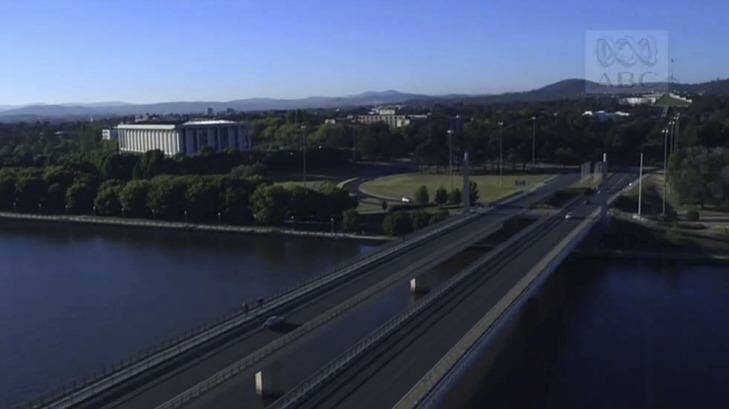 The opening shot of Canberra in Episode 1 of The Code: an aerial view of a car crossing Commonwealth Avenue bridge towards Parliament House.