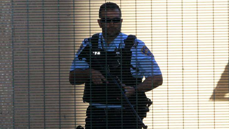 A heavily armed police officer prepares to escort Omarjan Azari at Sydney's Central Local Court. Photo: Daniel Munoz