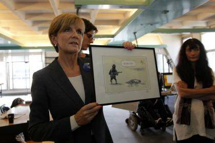 Julie Bishop shows off the cartoon before presenting it to the survivors of the Charlie Hebdo attack. Photo: Antoine Gyori