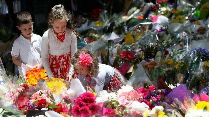A girl adds flowers to the tributes at Martin Place. Photo: Daniel Munoz