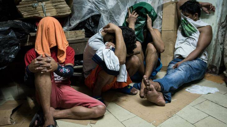 Alleged drug suspects cover their faces during a drug raid on December 9, 2016 in Manila, Philippines.  Photo: Dondi Tawatao/Getty Images
