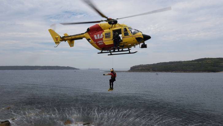 Rescue crewman John Molnar offers a thumbs up signal as he descends during a winch training exercise at Cape Banks. Photo: Nick Moir