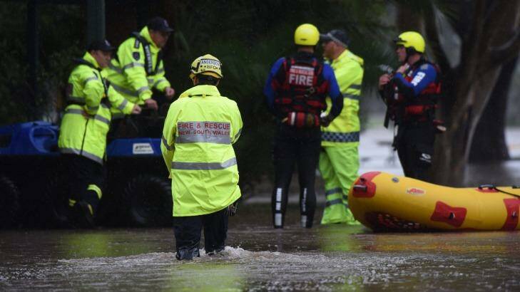 Fire crews with an inflatable boat talk to police during flooding at Raymond Terrace on Wednesday. Photo: Nick Moir