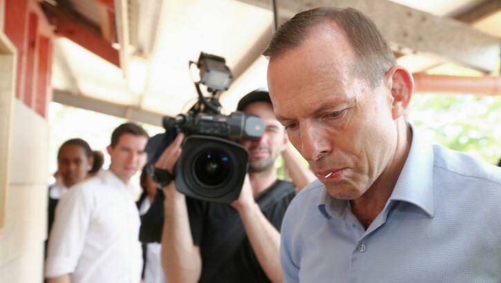 Prime Minister Tony Abbott, nail in his mouth, gets to work helping to build a cubby house during his visit to Bamaga Senior School, Cape York, on Wednesday. Photo: Alex Ellinghausen