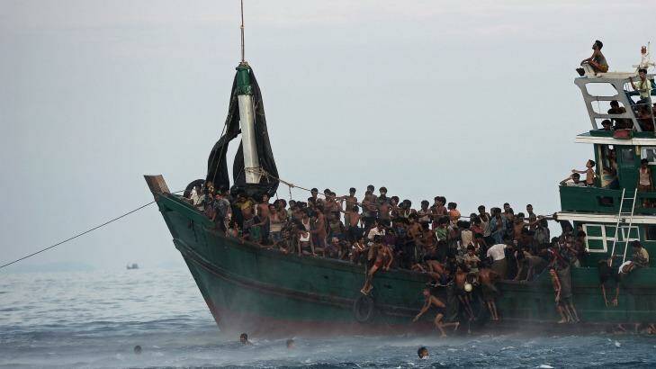 Rohingya migrants jump from their overcrowded vessel after a food drop.  Photo: Christophe Archambault