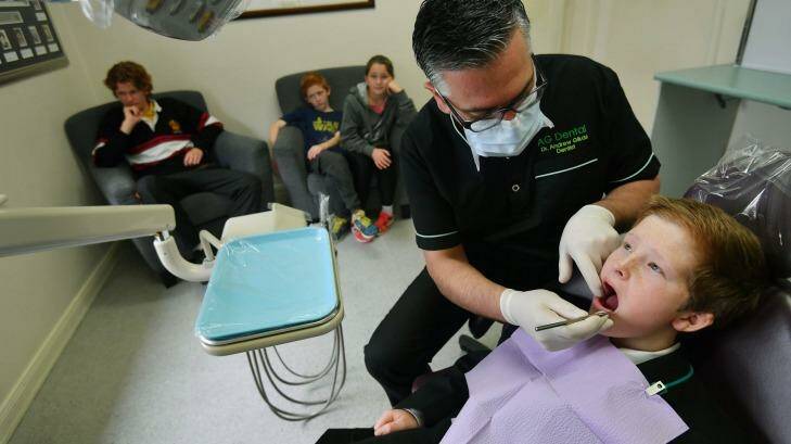 Dentist Dr Andrew Gikas with the Grenville family, Henry in the chair. Photo: Joe Armao