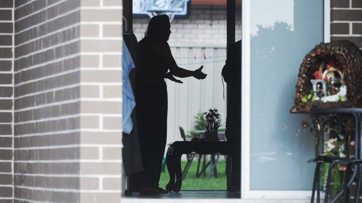 A woman argues with police as her home is raided in Fairfield Heights. Photo: Nick Moir