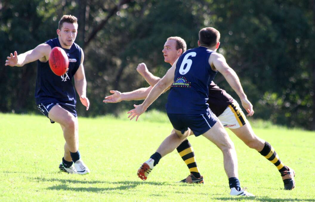 PASS: Tigers Jeremy O’Byrne hand balls to a team mate despite pressure from Nowra opponents.