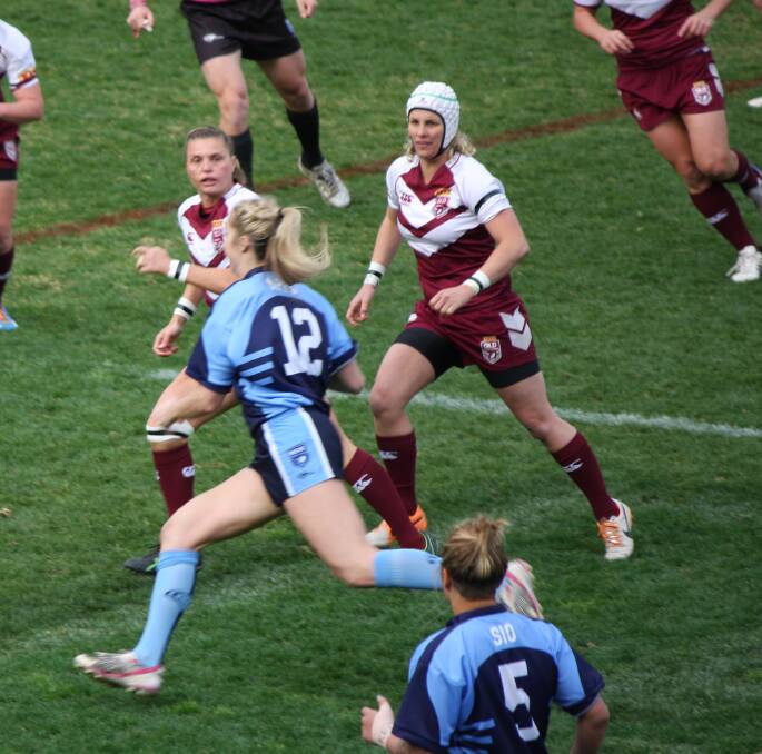 Bega's Kezie Apps sidesteps two Queensland defenders during one of several strong runs she made for the NSW full contact women's team last Saturday. 