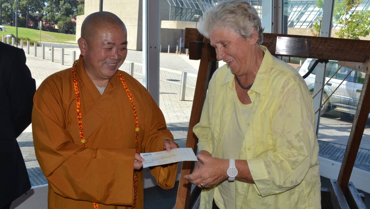 Shoalin Abbot Shi Yongxin presents Shoalhaven Mayor Joanna Gash with the final payment for the land at Comberton Grange on February 23.