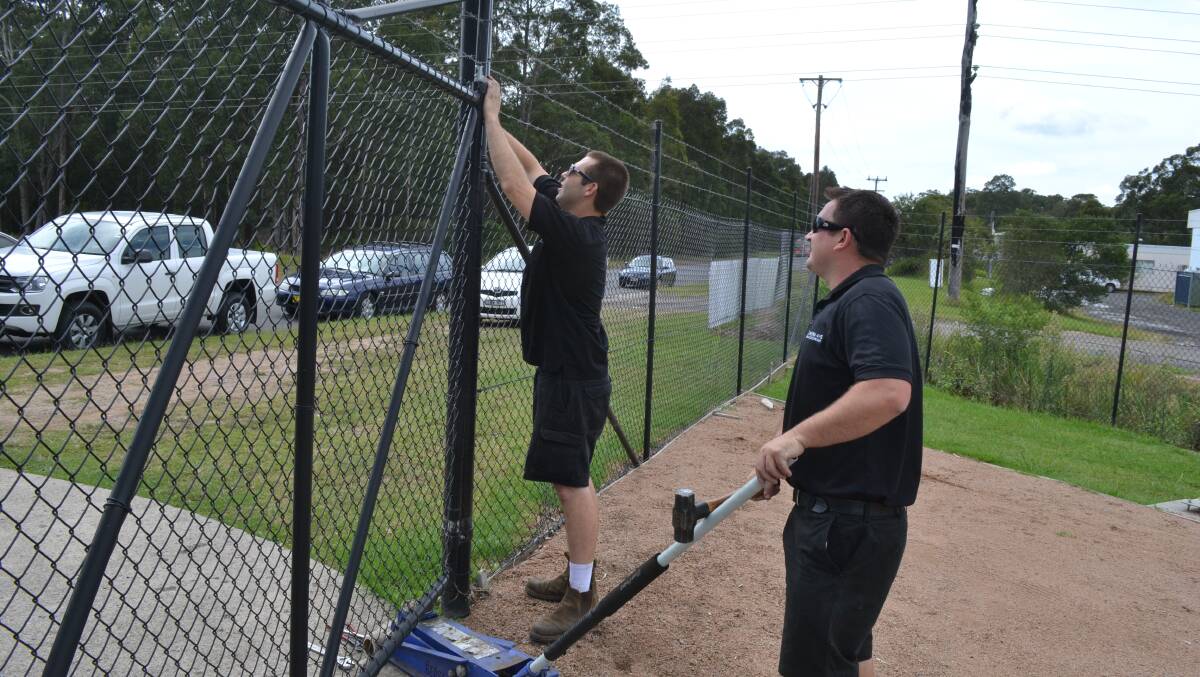 Staff members repair the fence knocked down by ram raiders at 4WD and Outdoor products on Flinders Road, South Nowra.