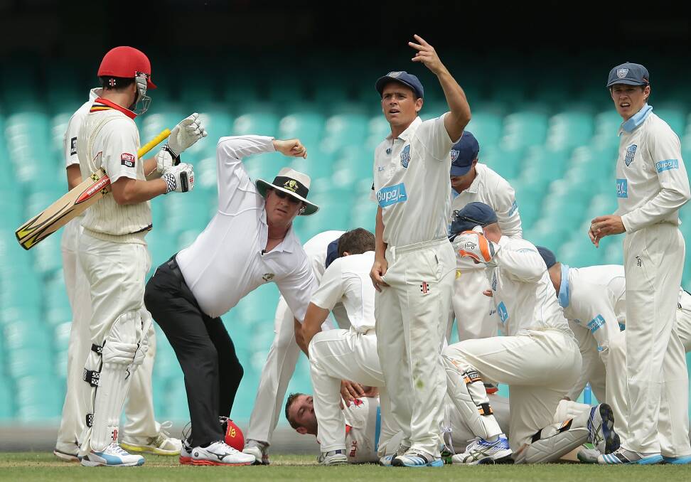 SICKENING BLOW: Umpires and players call for help after Phil Hughes was struck by a bouncer at the SCG on Tuesday. Photo: GETTY IMAGES  