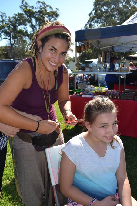 Rosanna Swarts carefully braids the hair of Vanessa Parker from Sydney at the White Sands Easter Festival at Huskisson on Saturday.  