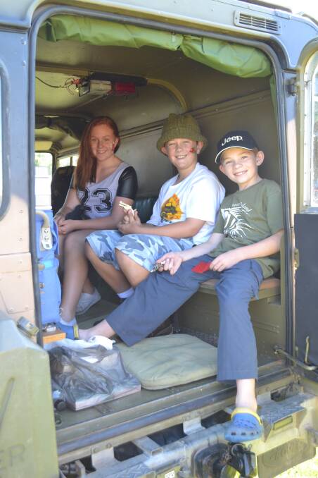 Bethany Kickert, Marshall Kickert and Aaron McCann from Sydney have a ride in one of the display army trucks at the White Sands Easter Festival at Huskisson on Saturday. 