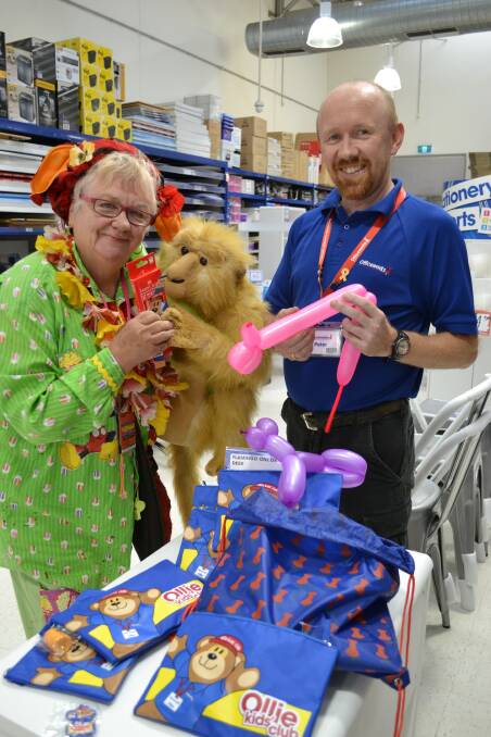 BRIGHT OFFERINGS: Officeworks store manager Peter Fanning hands over children’s packages to Mazza the clown, aka Marilyn Beaven-Williams.