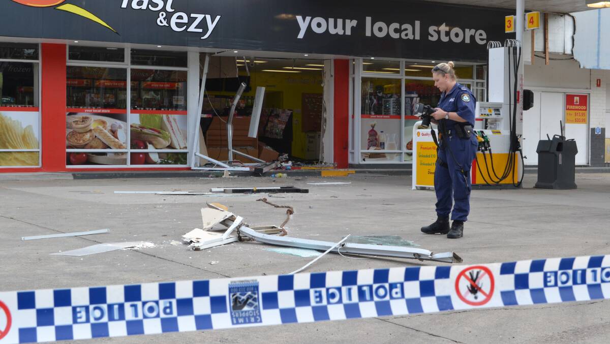 GATHERING EVIDENCE: Nowra crime scene officer senior constable Pep Reid photographs the crime scene at the Shell garage at Wandandian.