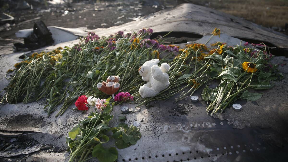 Flowers and mementos lie on wreckage at the crash site of Malaysia Airlines Flight MH17, near the settlement of Grabovo in the Donetsk region on July 19. Picture: REUTERS