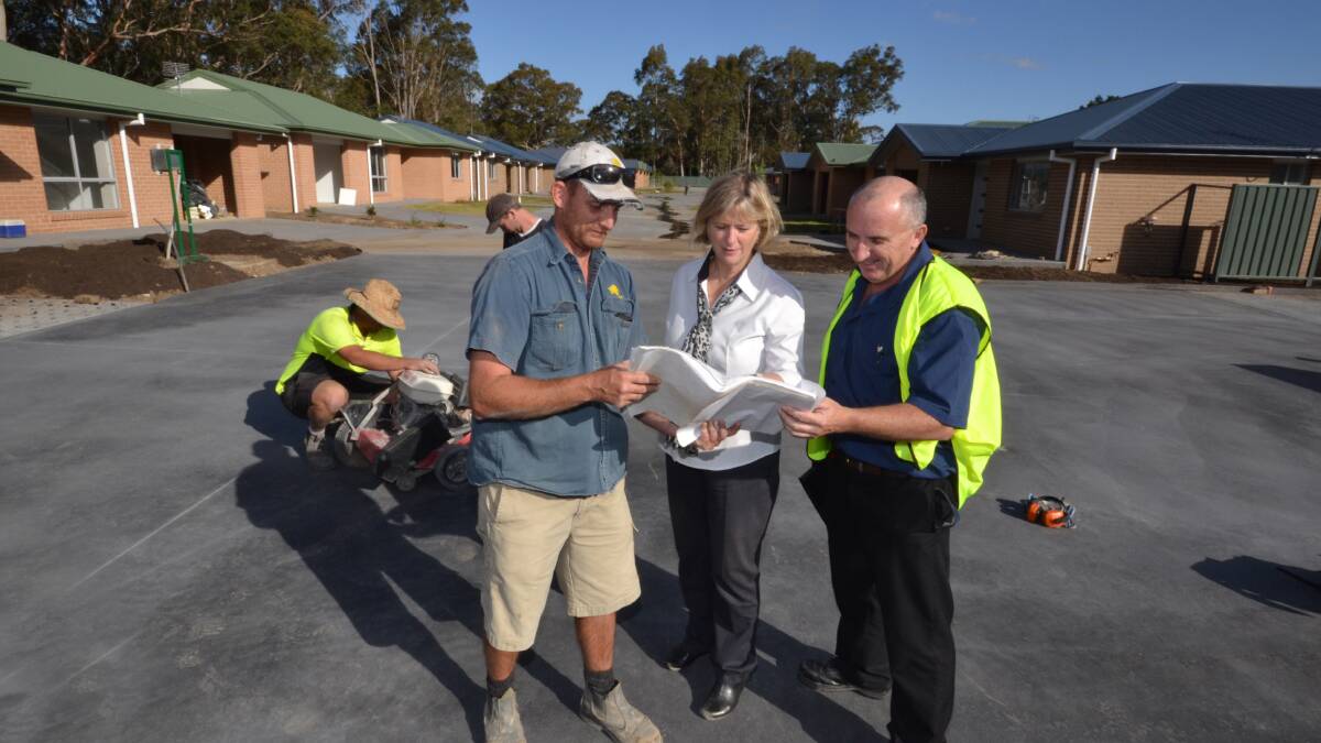 Site foreman Luke Downes, Southern Cross Community Housing CEO Marg Kaszo and asset manager Gary Watkins take a closer look at the 19 community housing units on Yalwal Road. The development is nearing completion on time and on budget. However budget cuts placed future projects in doubt.