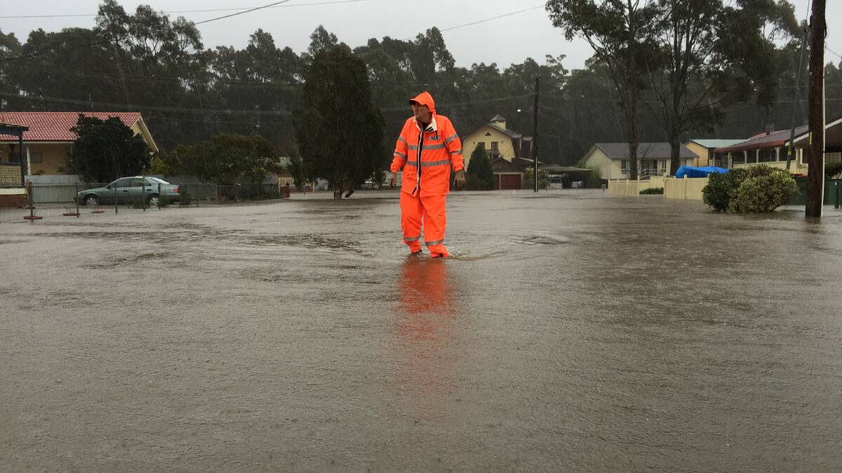 DANGER ZONE: St Georges Basin SES volunteer Chris Wheeler makes his way through floodwaters in The Park Drive, Sanctuary Point. Photo: ADAM WRIGHT