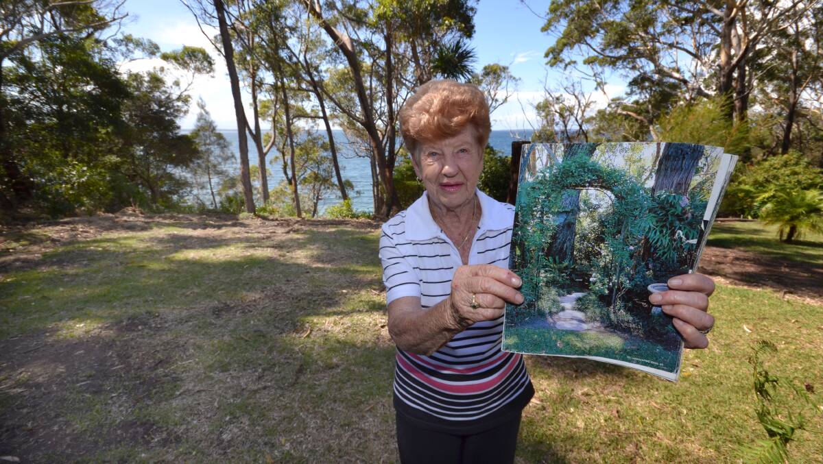 HEARTBROKEN: Eileen Taylor on the Orion Beach reserve where, before last week, stood her award-winning garden. She is holding a magazine article that featured her former garden.