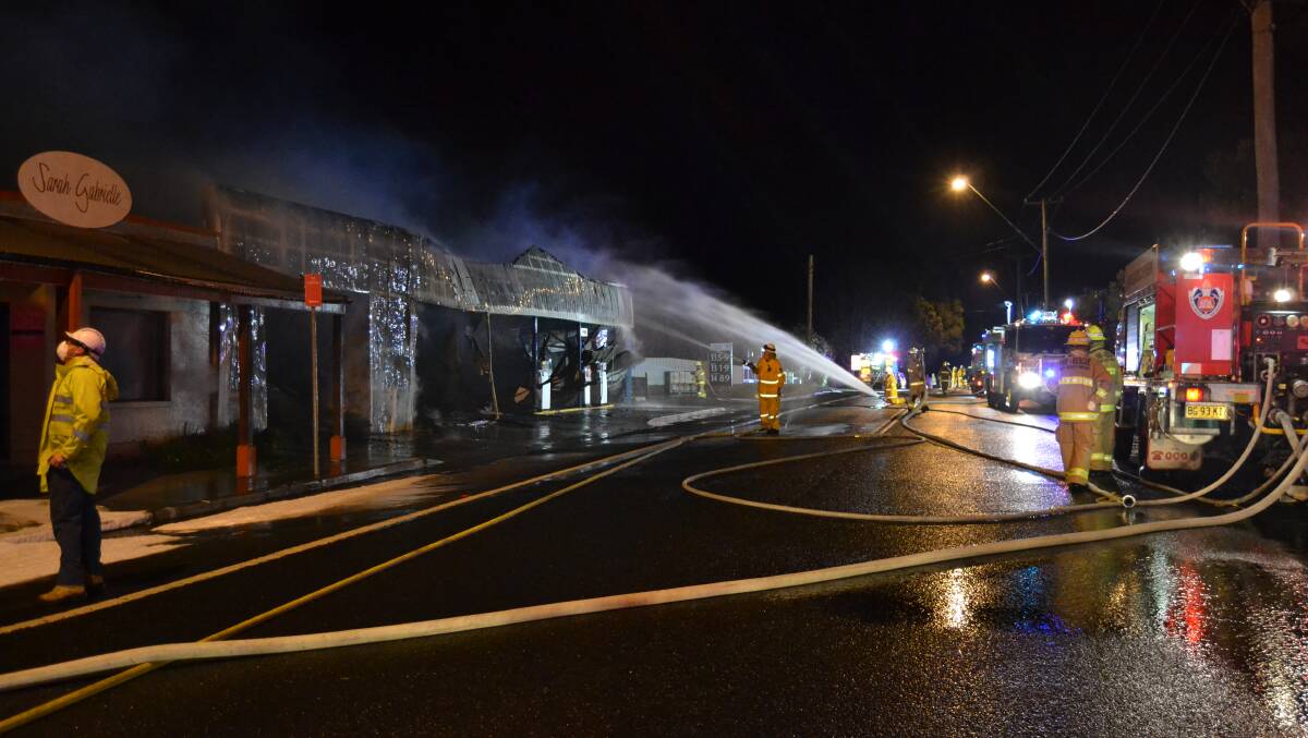 BLAZE: Firefighters douse the building that housed the Milton Tyre Service.