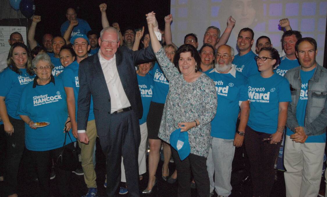 VICTORY: Flanked by the blue army of campaign volunteers, Gareth Ward and Shelley Hancock savour their election wins at the Bomaderry Bowling Club on Saturday night.
