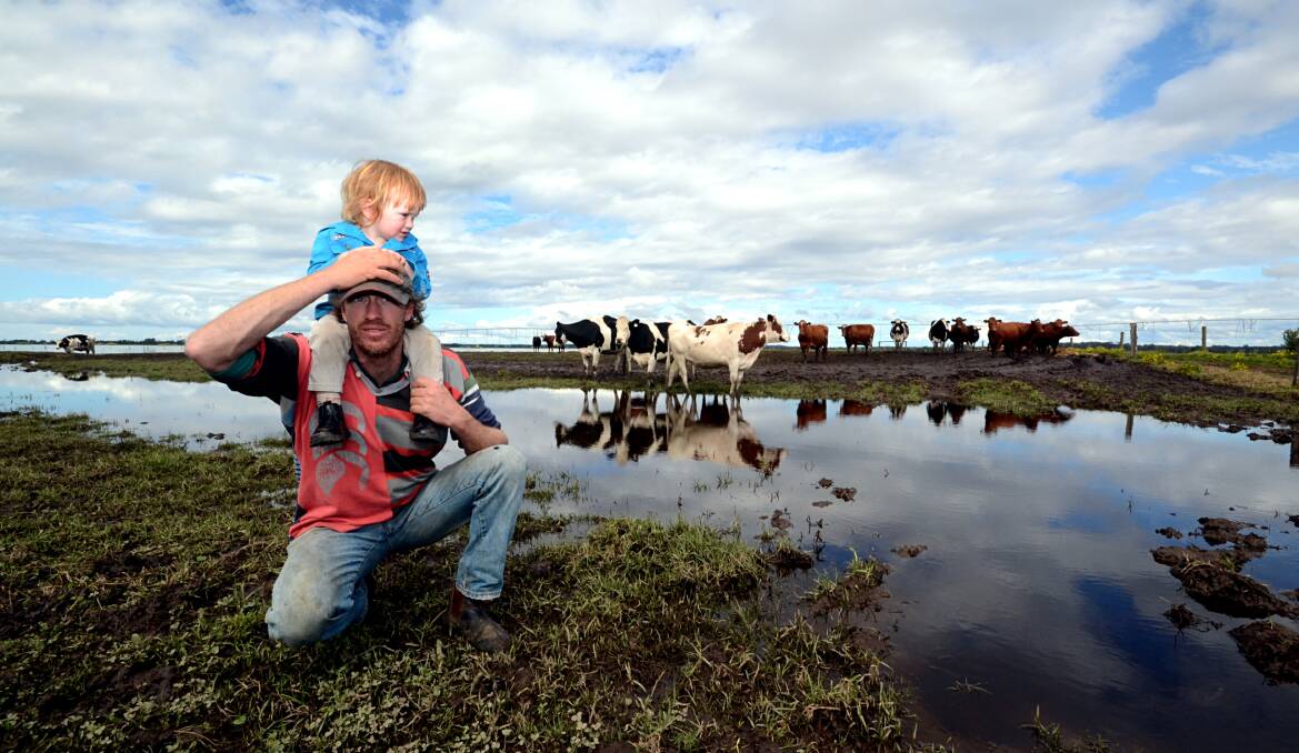 WATER WORLD: Dairy farmer Tim Cochrane surveys the floodwaters on his family farm at Numbaa with his two-year-old son Cody.