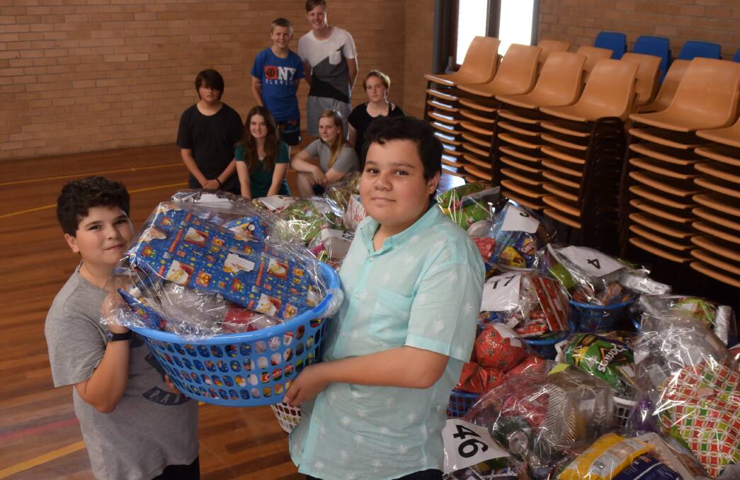 GREAT CAUSE: Josh Leuzzi and Matthew Taufa, along with many other volunteers from St John the Evangelist, help pack Christmas hampers.