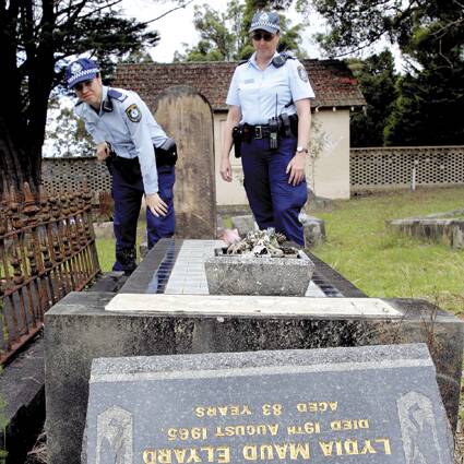 SECURITY: Constable Vicki Ferraris and Senior Constable Wendy Elrihaw inspect the Nowra Cemetery for vandalism, although relatives believe this headstone simply fell.