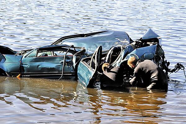 GRIM TASK: Divers inspect the wrecked car.