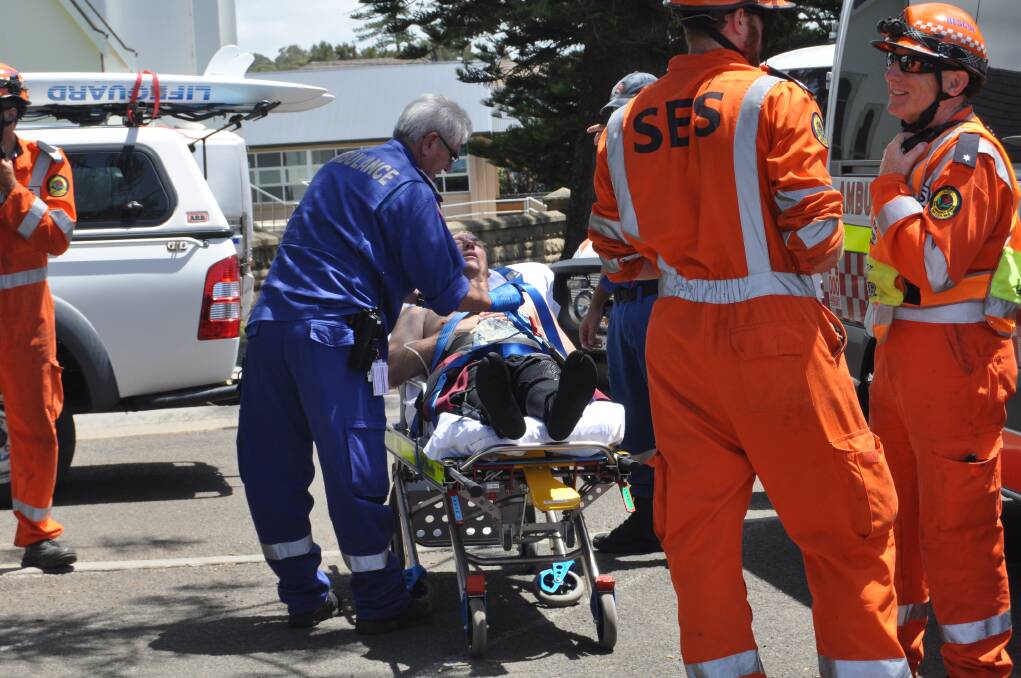 A paramedic treats the man before taking him to Shellharbour Hospital. Picture: DANIELLE CETINSKI