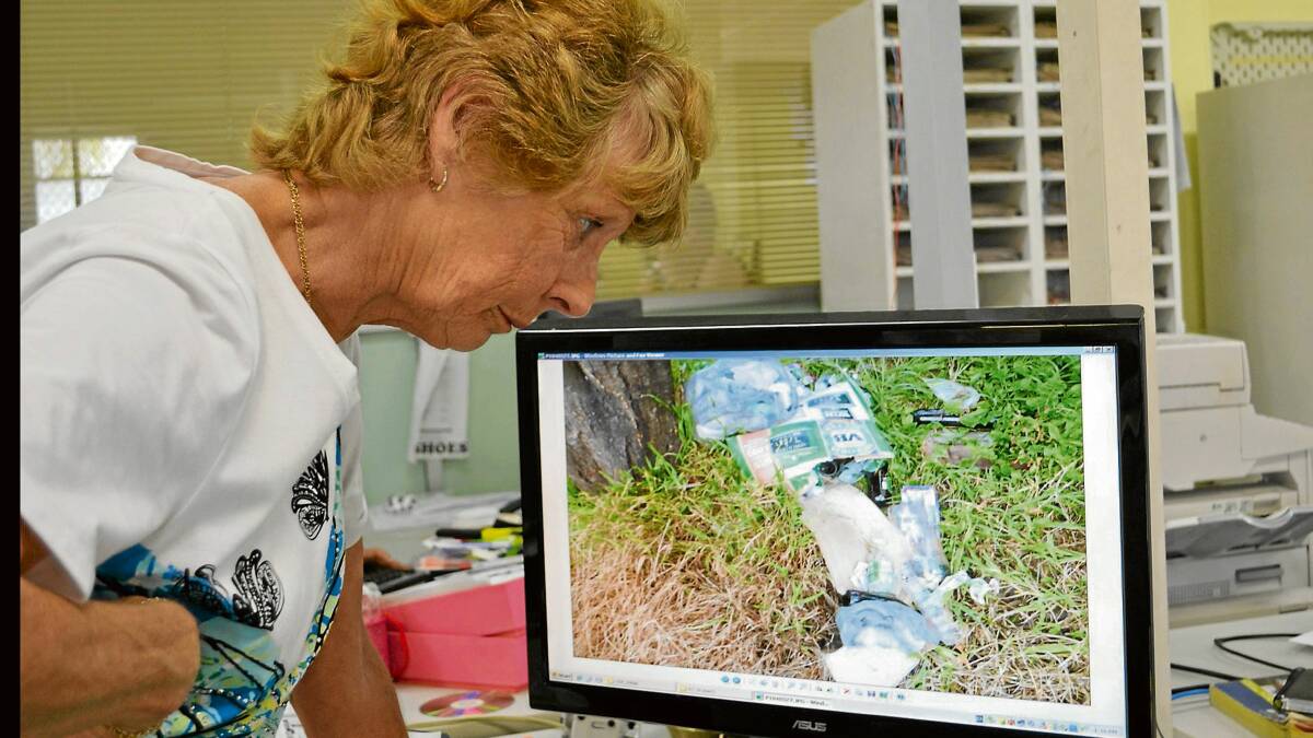 NOT A PRETTY PICTURE: North Nowra resident Michelle Ford looks at a photo of some of the rubbish left on a beach area fronting the Shoalhaven River.