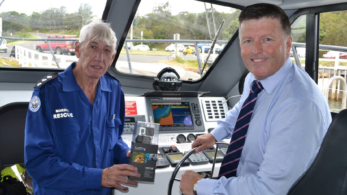 PHOTO OPPORTUNITY: Minister for Police and Emergency Services Michael Gallacher (right) at the helm of the Marine Rescue Shoalhaven rescue vessel AM McGilvray 2 presents the first of 70 GoPro cameras to be rolled out across the state to Marine Rescue Shoalhaven unit commander Terry Watson.