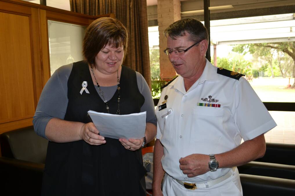 SPECIAL GUEST: Guest speaker Louise Williams shows Warrant Officer David Larter some of the statistics relating to White Ribbon Day during a morning tea at HMAS Albatross on Monday.