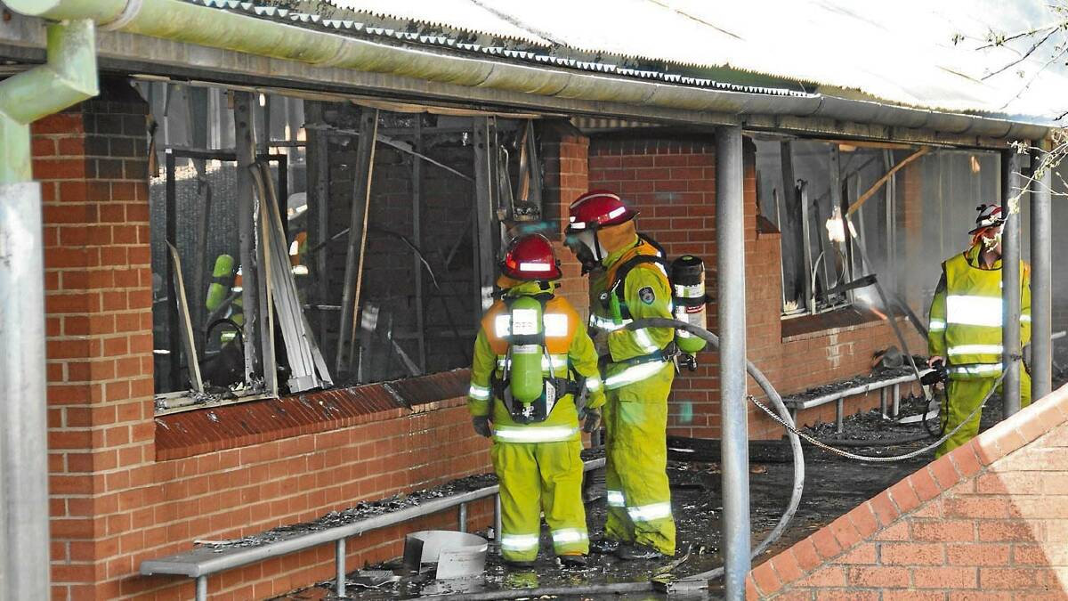 RUINED: Firefighters work on extinguishing a blaze which destroyed four classrooms at St Georges Basin Public School yesterday.
