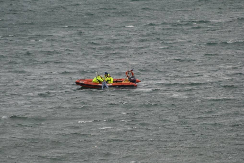 Marine rescue volunteers drag a man into their inflatable after his tinnie had capsized near Crookhaven Head.