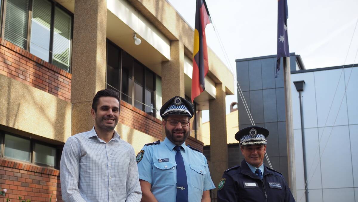 From left to right, Aboriginal Employment and Engagement Team manager Reece Craigie, South Coast Police District Acting Inspector Luke Geradts and Assistant Commissioner Joe Cassar standing in front of the Aboriginal flag.