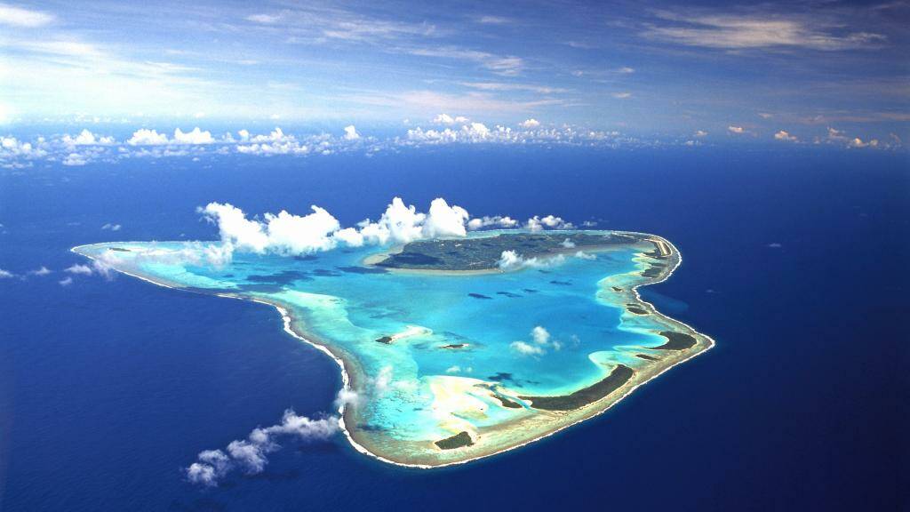 BEYOND THE REEF: Aerial view of Aitutaki Island showing the Aitutaki mainland, reef, lagoon and 15 uninhabited islets within the lagoon. Image: supplied.